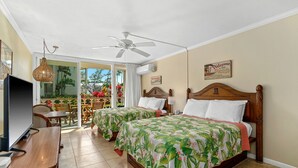 A hotel room with two beds, a ceiling fan, a TV, and a view of the outdoors.