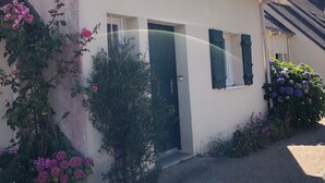 Ein eingeschossiges Gebäude mit Satteldach, einer Haustür und einer kleinen Veranda.