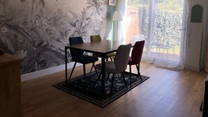 Ein Essbereich mit Tisch und Stühlen, einer Wand mit Muster, einem Fenster mit Vorhängen und einem Holzboden.
