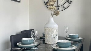 Una mesa puesta con platos azules y un jarrón blanco con flores secas.