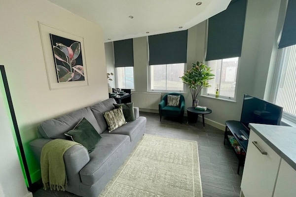 A relaxing open-plan living space with a Smart TV offering Netflix and a comfortable sofa bed. The layout includes a small dining nook and a combined kitchen and lounge area, creating a practical and inviting place to unwind.