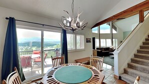Un espace repas comprenant une table ronde et des chaises, un lustre et une vue sur l’extérieur.