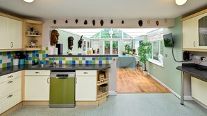 Una cocina con armarios blancos, un lavavajillas verde y un salpicadero de azulejos.