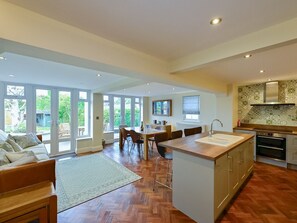 A spacious kitchen with a central island, large windows, and a dining area with a view of the garden. - Stylish 3-Bed in Historic Caerleon-Garden+Parking | Pass The Keys (Newport)