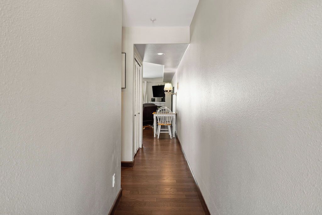 A narrow hallway with wooden flooring and white walls.