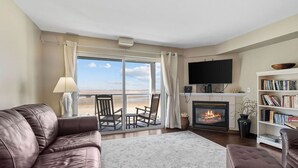 A living room with a fireplace, a television, and a bookshelf. - Beautiful Luxury Bay View Condo! (Lincoln City)