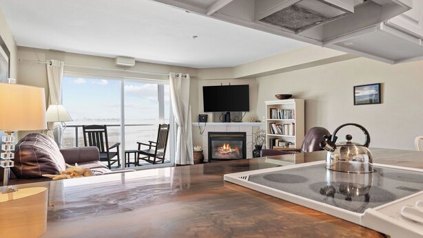 A living room with a fireplace, a flat-screen TV, a bookshelf, and a dining area with a table and chairs. - Beautiful Luxury Bay View Condo! (Lincoln City)