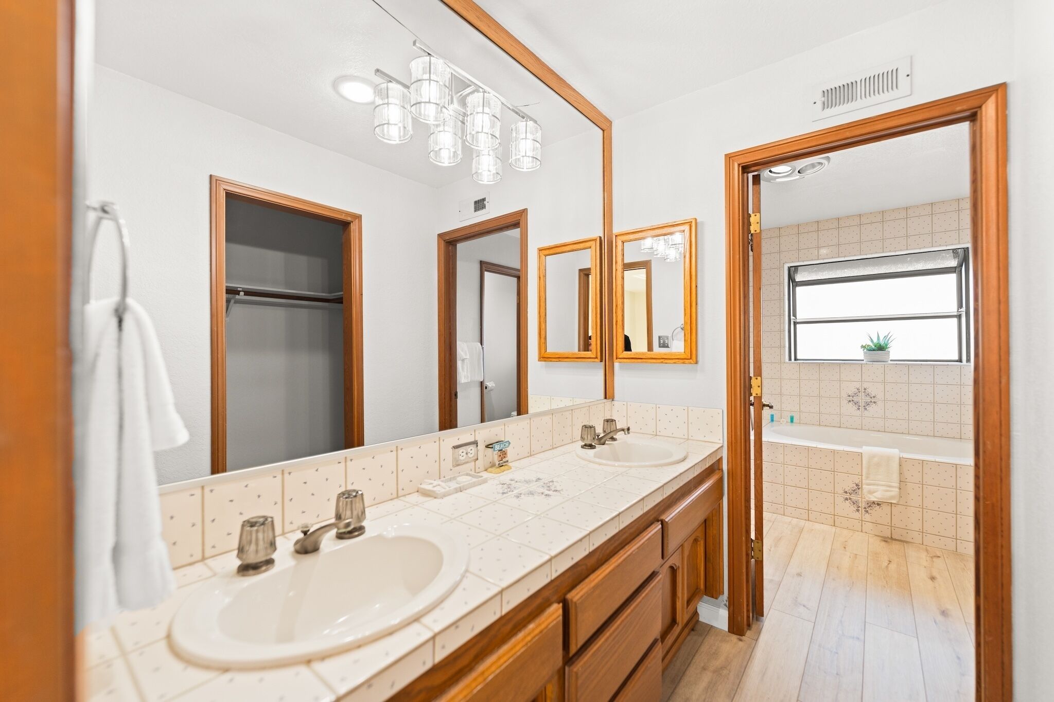 A modern bathroom with two sinks, a large mirror, and a view of the bathroom through a glass door.