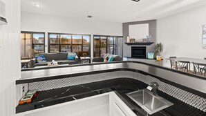 A modern kitchen with a black and white tiled backsplash, a built-in sink, and a dining area with a table and chairs. - 25%Off30+ Stay! Channel Islands Harbor Great Views (Oxnard)