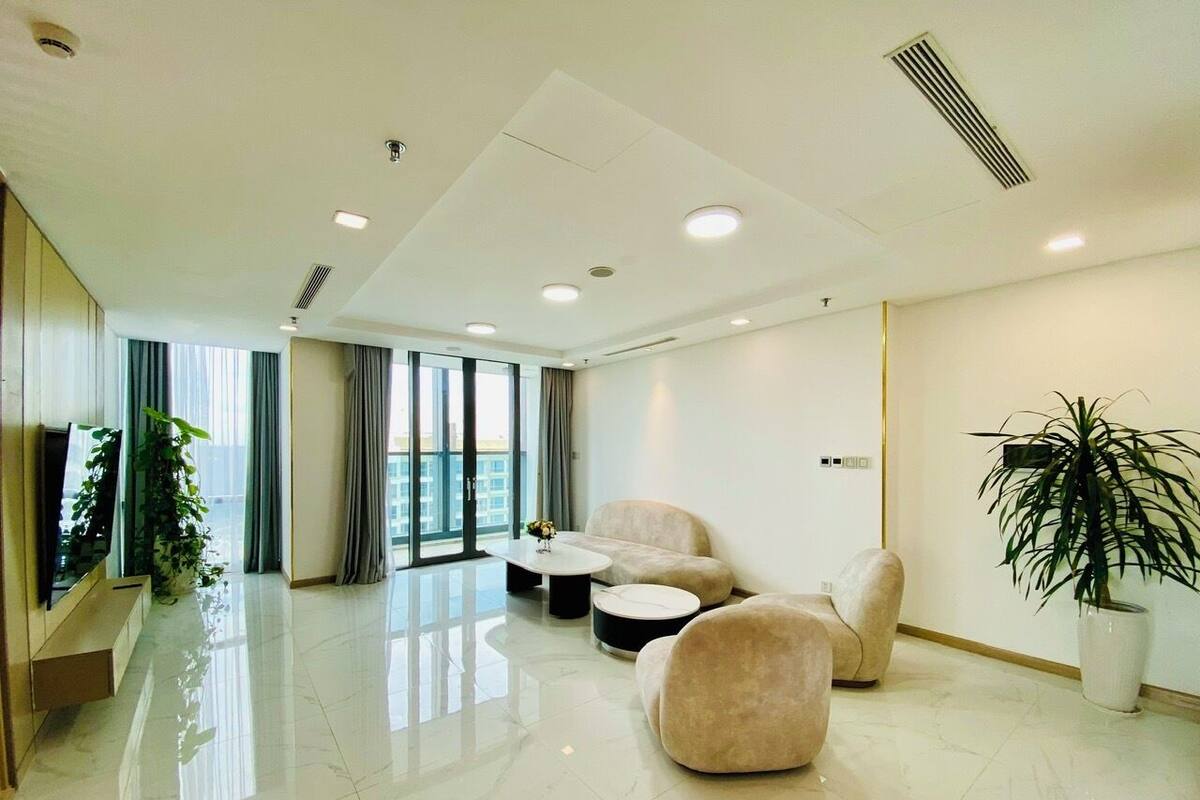 A modern hotel lobby with a large window, plush seating, a flat-screen TV, and a potted plant.