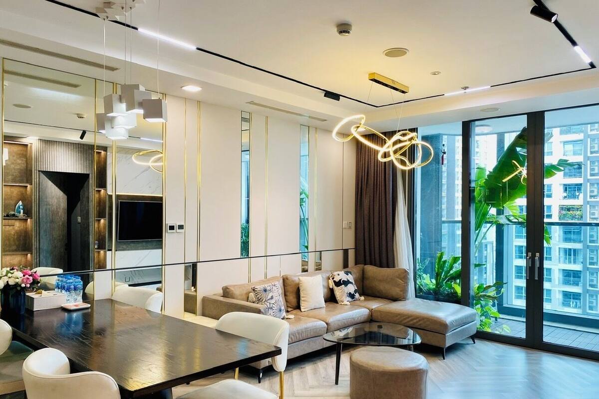 A modern living room with a sofa, a dining table, and a large window with a view of buildings.