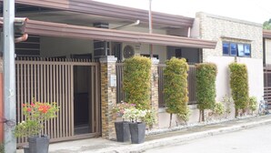 A building with a gated entrance, a covered walkway, and potted plants along the wall. - Efas Guesthouse Tagum City (Tagum)