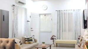 A modern living room with a sofa, dining table, and chairs, a wooden ceiling, and a door with curtains. - Efas Guesthouse Tagum City (Tagum)