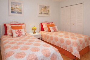 Une chambre double avec deux lits, chacun équipé de la même literie et des mêmes oreillers, une table de chevet avec une lampe et une armoire.
