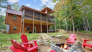 A wooden cabin with a stone fire pit and red Adirondack chairs in the yard. - Deerly Blissed, Blue Ridge (Blue Ridge)