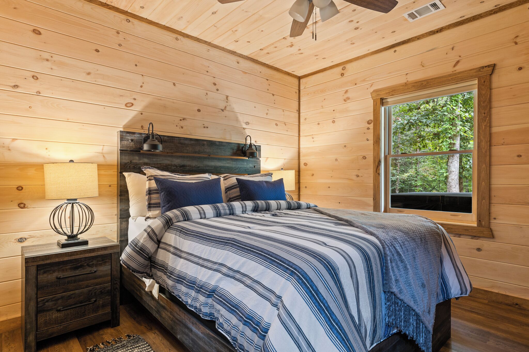 A wooden cabin bedroom with a bed, nightstands, and a window.