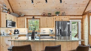 A wooden cabin kitchen with granite countertops, stainless steel appliances, and a large island with bar stools. - Deerly Blissed, Blue Ridge (Blue Ridge)