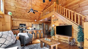 A cabin interior with a living room, kitchen, and a staircase.