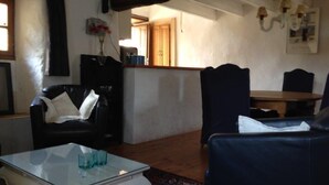 A living room with a glass coffee table, a black leather sofa, a blue armchair, and a dining area with a wooden table and chairs. - Maison Geo 2: Renovated MAS for max 6 pers with one of the most beautiful pools (Saint-Mélany)