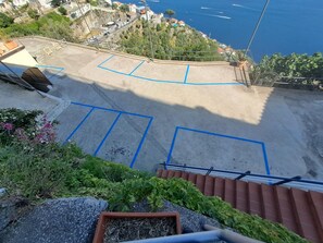 A view of a coastal area with a paved area marked for parking, a staircase leading down, and a railing.