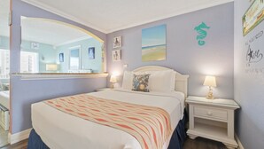 A hotel room with a large bed, two bedside tables, a mirror, and artwork on the walls. - Pelican Pointe 414:Walk to Beach~Pool~Free Parking (Clearwater Beach)