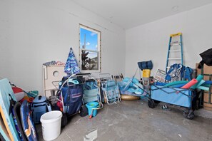 A cluttered room with various items including a ladder, a cart, and a window with a view of a building.