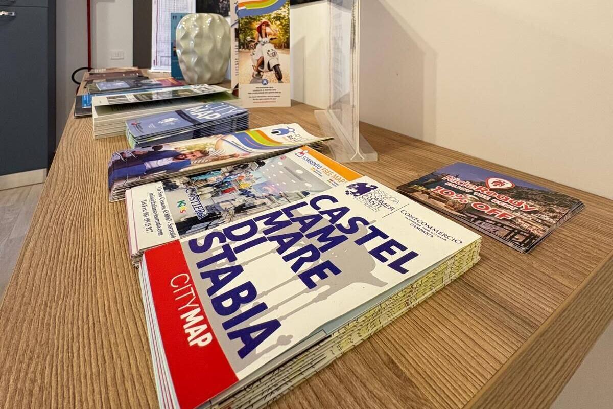 A room with a large cityscape poster, a wooden table with magazines, and a clear glass display case.
