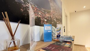 A reception desk with a cityscape mural, brochures, and a glass bottle of reed diffuser. - Domus Matronae (Castellammare di Stabia)