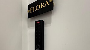 A door with a black sign labeled 'FLORA' and a black electronic keypad below it. - Domus Matronae (Castellammare di Stabia)