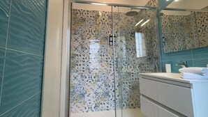 A modern bathroom with a glass shower enclosure, a white vanity, and a large mirror. - Domus Matronae (Castellammare di Stabia)