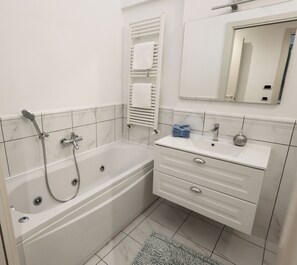 A modern bathroom with a bathtub, a sink, and a mirror. - Prestige appartamens (Viareggio)