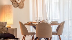 Un coin repas avec une table ronde dressée pour quatre personnes, entourée de chaises rembourrées.