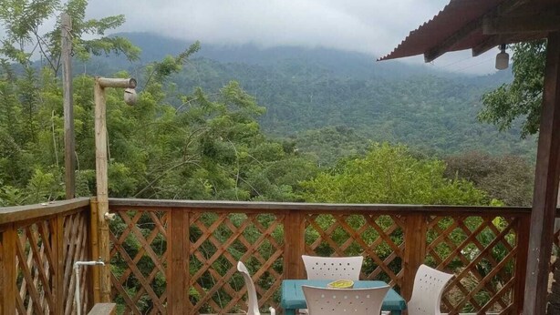 A patio with a table and chairs, overlooking a mountainous landscape. - Selva Maria Tayrona  (Santa Marta)