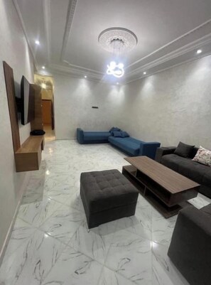 A modern living room with a sectional sofa, a coffee table, and a TV mounted on the wall. - Résidence Atlantic (Agadir)