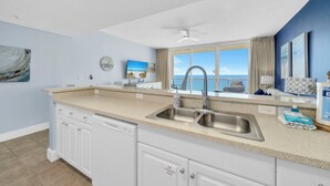 A kitchen with a large window, a sink, and a dishwasher.