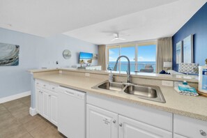 A kitchen with a large window, a sink, and a dishwasher.
