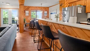 Een moderne keuken met houten lambrisering, een bar met krukken, en uitzicht op het omliggende landschap.