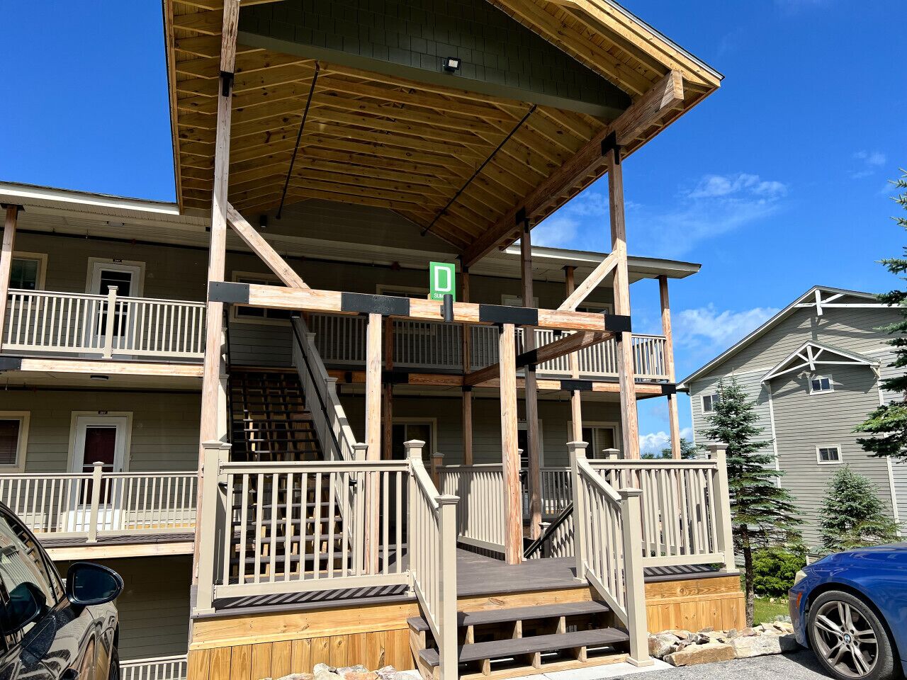 A multi-story building with a wooden deck, a covered outdoor area, and a staircase leading to the upper floors.
