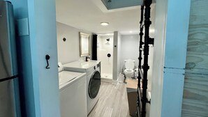 A compact laundry room with a washing machine, dryer, and a small sink. - Tiny house monthly rental with small office in central North Charleston with AC (North Charleston)