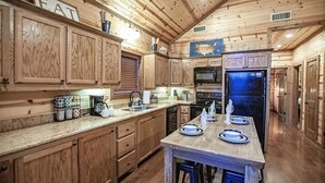 A wooden cabin-style kitchen with wooden cabinets, a central island, and a built-in microwave.
