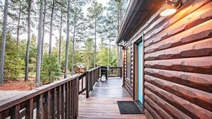 A wooden deck leading to a cabin with a blue door, surrounded by tall trees.
