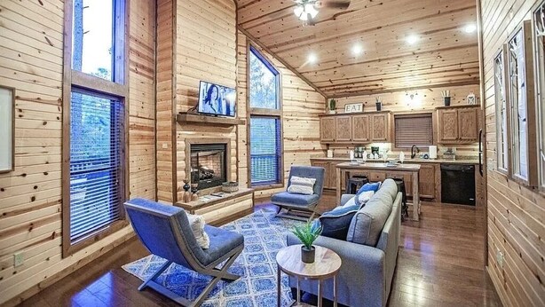 A log cabin interior with a living room, kitchen, and dining area.