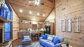 A cozy cabin interior with a dining area, kitchen, and seating space.