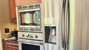 Una cocina con refrigerador de acero inoxidable, horno doble y cafetera.