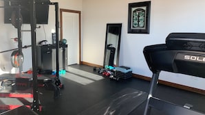 Uma academia em casa com esteira, banco de musculação e diversos equipamentos de exercício.