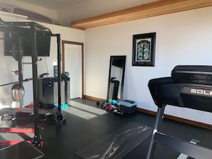 Ein Heimfitnessraum mit Laufband, einer Gewichtbank und verschiedenen Trainingsgeräten.
