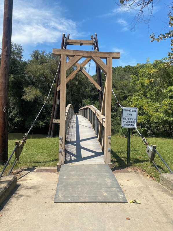 Un puente peatonal colgante con un letrero que indica que no se permite correr ni saltar.