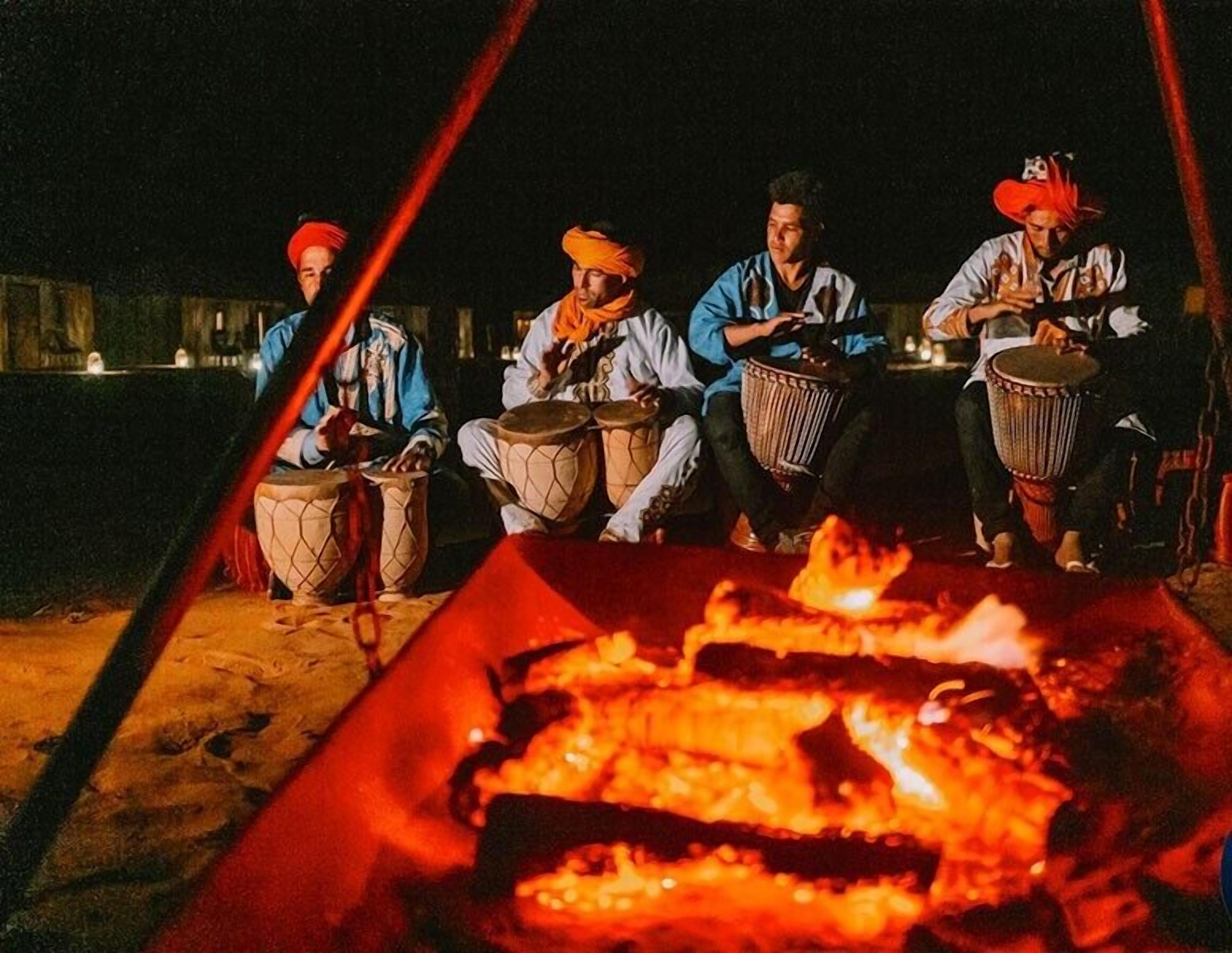 Cuatro personas sentadas alrededor de un brasero tocando la batería.