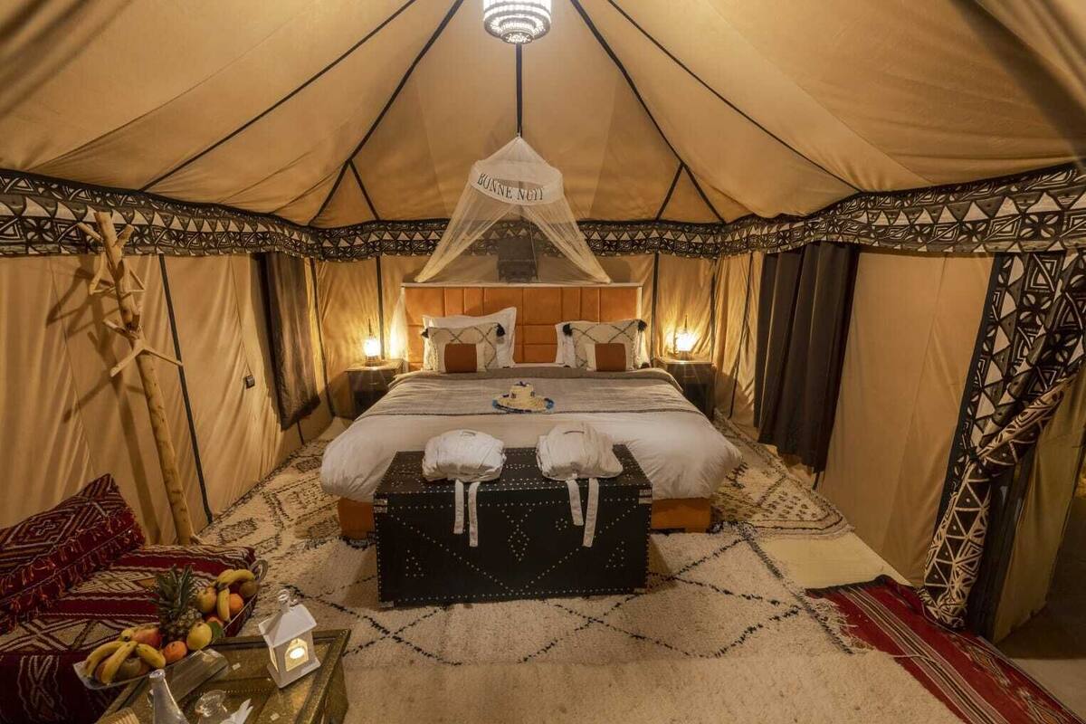 Una habitación con carpa, una cama, mesitas de noche y un mosquitero colgado.