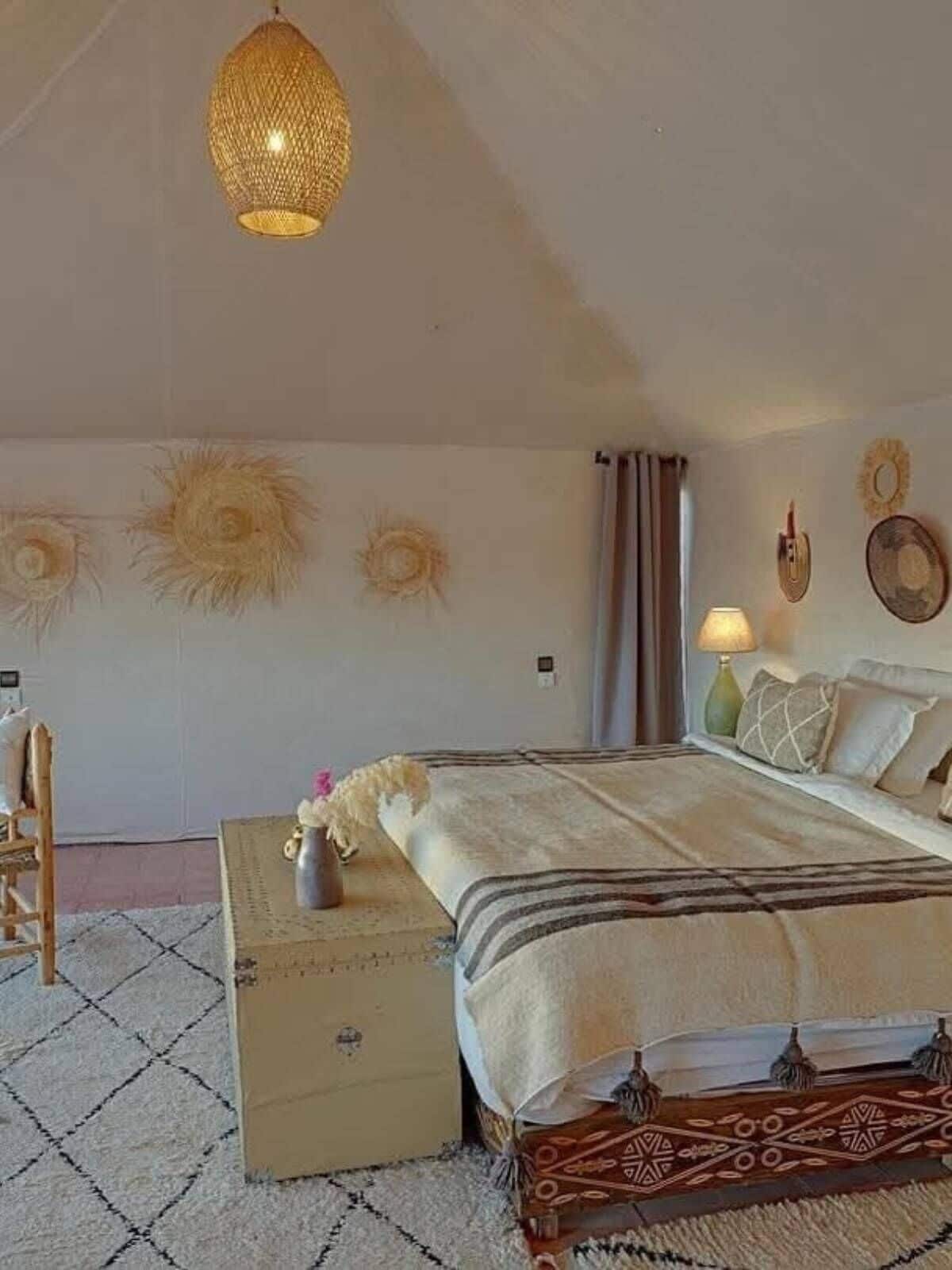 Quarto com cama, mesa de cabeceira, luminária e decorações nas paredes.